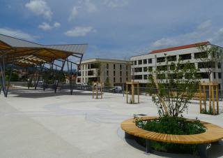 Photo d'un quartier nouveau, avec une place, des bâtiments d'habitation, une halle et des espaces verts