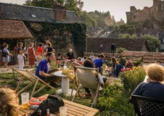 Des personnes installée dans un jardin, avec vue sur un chateau