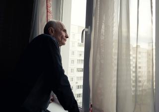 Un homme agé regarde par la fenetre 