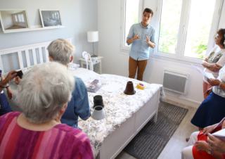 Des personnes dans une chambre à coucher écoutent un jeune homme