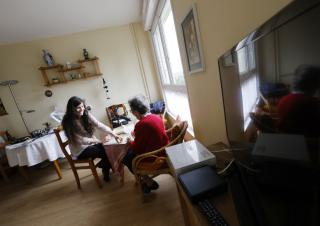 Une jeune femme et une femme âgée sont assises à une table dans une salle à manger de collecitité