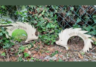 Des cadres de bois en forme de silhouette de hérissons, perçée d'un rond au milieu, posées en bas de grillage