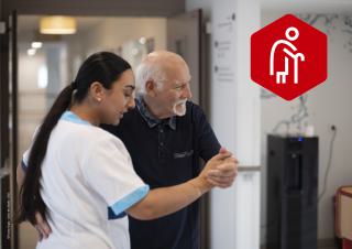 Une professionnelle de santé et une personne âgée se tiennent comme pour danser ou s'aider