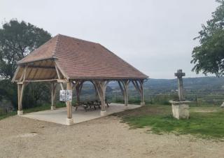 Une halle au toit de tuiles, point de vue ouvert sur le paysage, croix de pierre à côté de la halle