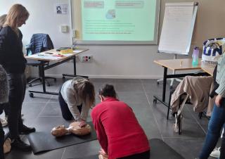 Des personnes pratique un massage cardiaque sur un mannequin au sol