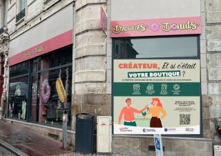 Une vitrine de magasin sur laquelle est posée une affiche: "créateur, et si c'était votre boutique?"