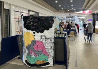 Hall de lieu public, au premier plan un dessin figurant une personne qui tient son visage dans ses mains