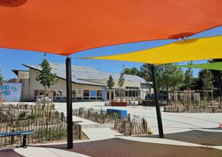 Un espace avec un sol clair et des toiles tendues  pour protéger du soleil