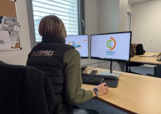 Une personne dans un bureau, face à deux écrans d'ordinateurs