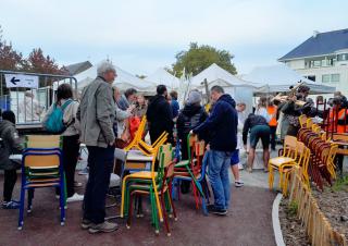 Une brocante en plein air, stocks de chaises et des personnes qui déambulent