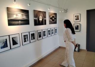 Un femme se tient face à des photos accrochées sur un mur blanc
