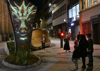 Des personnes dans une rue piétonne. En fond, un banc au design très moderne