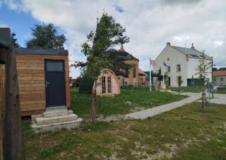 Des petits habitats de bois sur un espace engazonné, et en fond une bâtisse d'habitation
