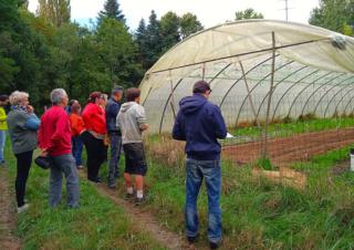 Des personnes se tiennent devant une serre-tunnel en plastique