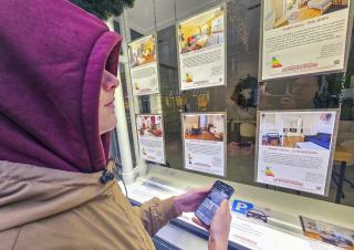 un jeune devant une vitrine d'agence immobilere 